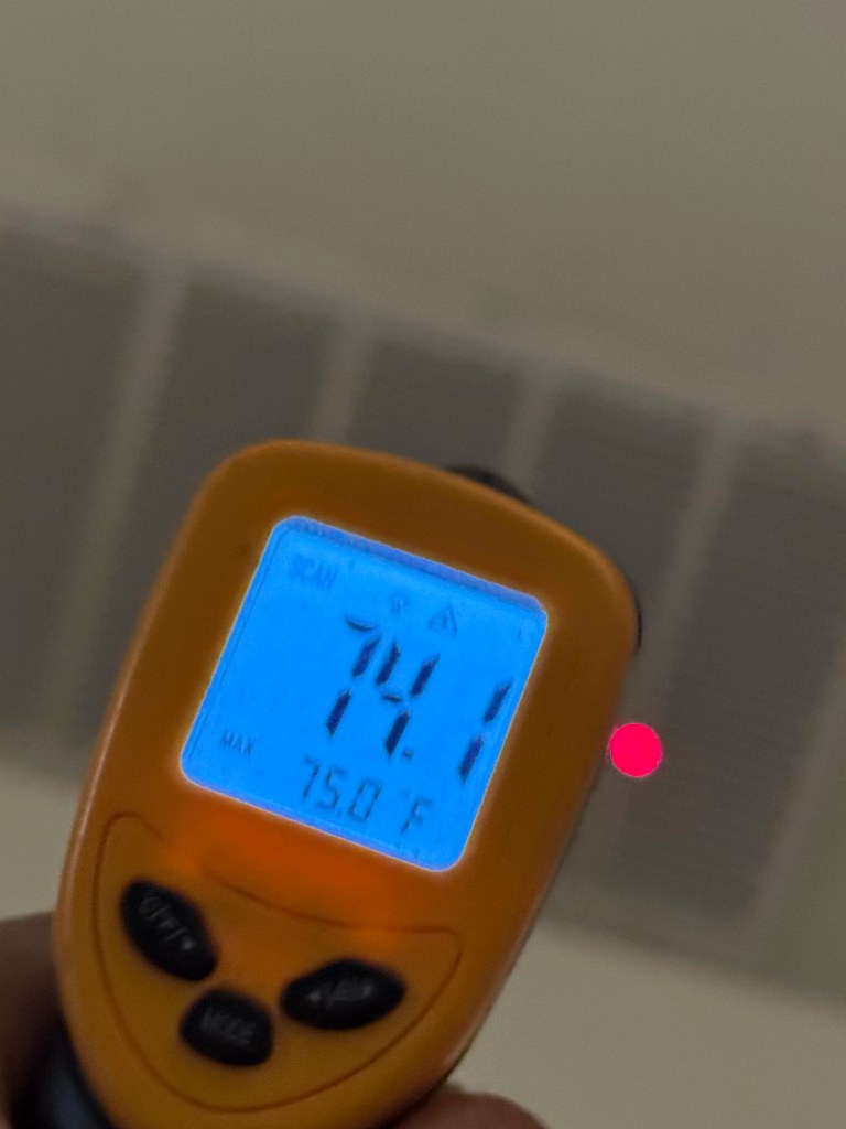 Digital infrared temperature gun showing 74.1°F in front of a ceiling supply vent